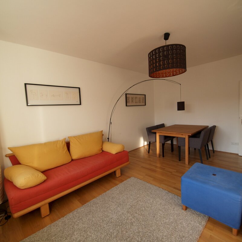 Wohnzimmer mit Ausziehcouch und Esstisch.