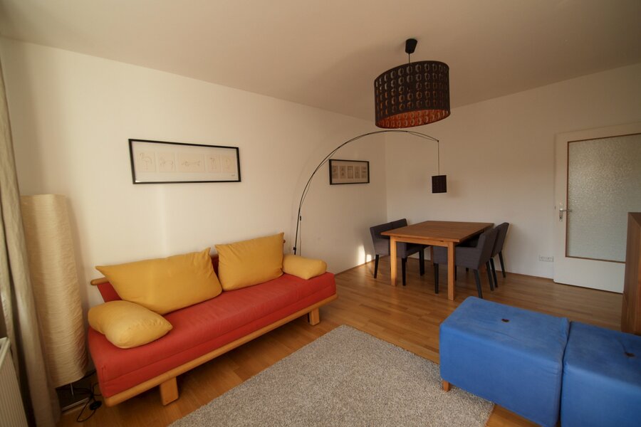 Wohnzimmer mit Ausziehcouch und Esstisch.