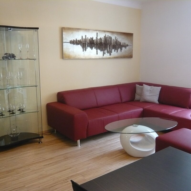 Living room with red leather sofa & glass cabinet – 2-room apt, short-term rental & temporary housing for 1 to 6 months in Vienna