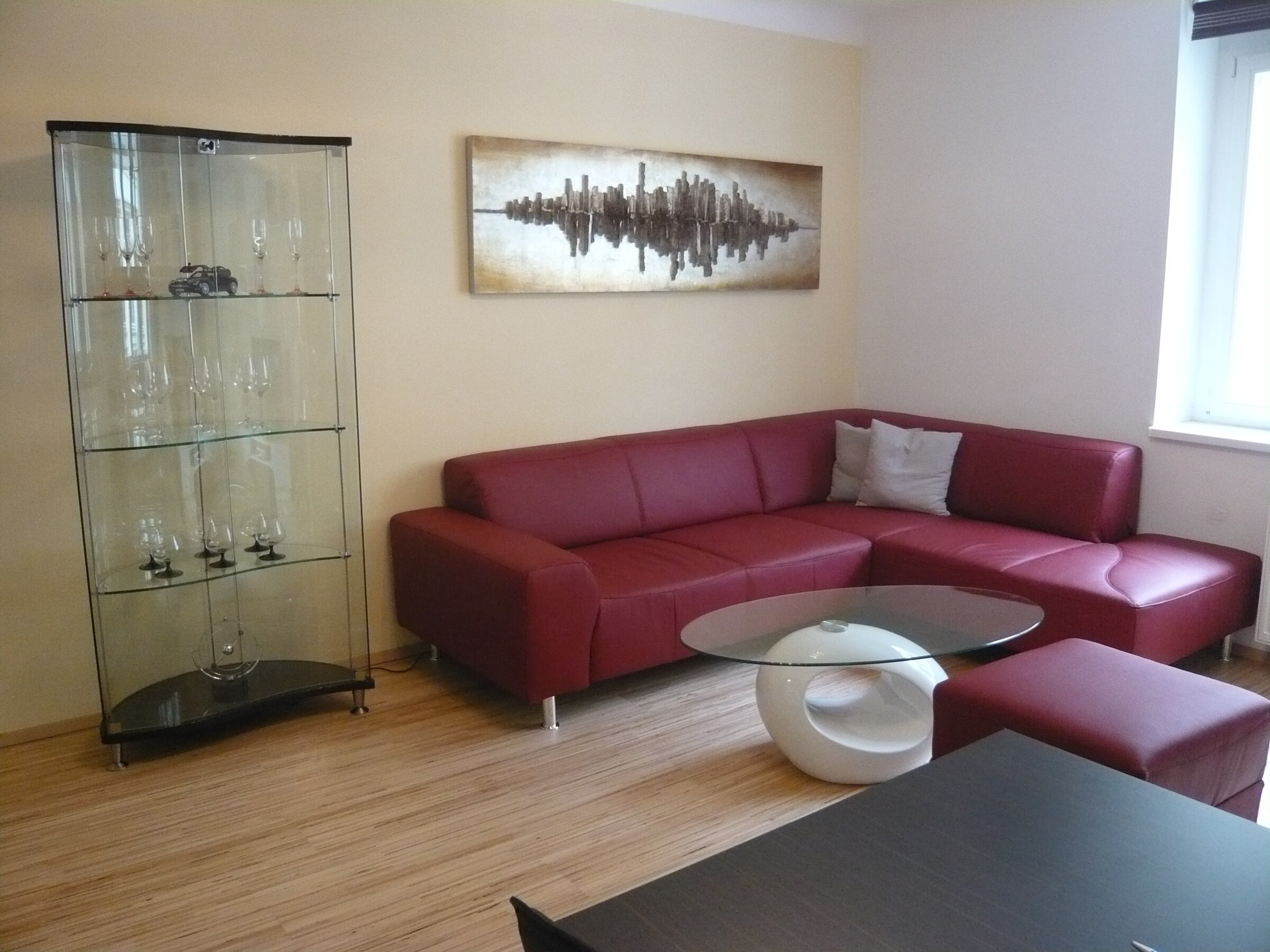 Living room with red leather sofa & glass cabinet – 2-room apt, short-term rental & temporary housing for 1 to 6 months in Vienna