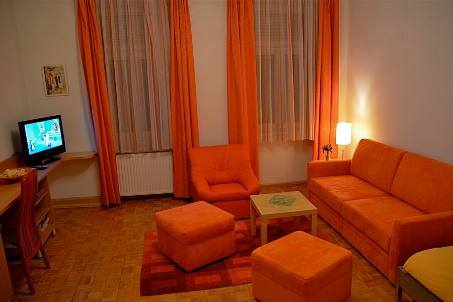 Wohnzimmer mit orangem Sofa & Sessel – 2-Zimmer Apartment, Kurzzeitmiete Wien, Wohnen auf Zeit 1 bis 6 Monate