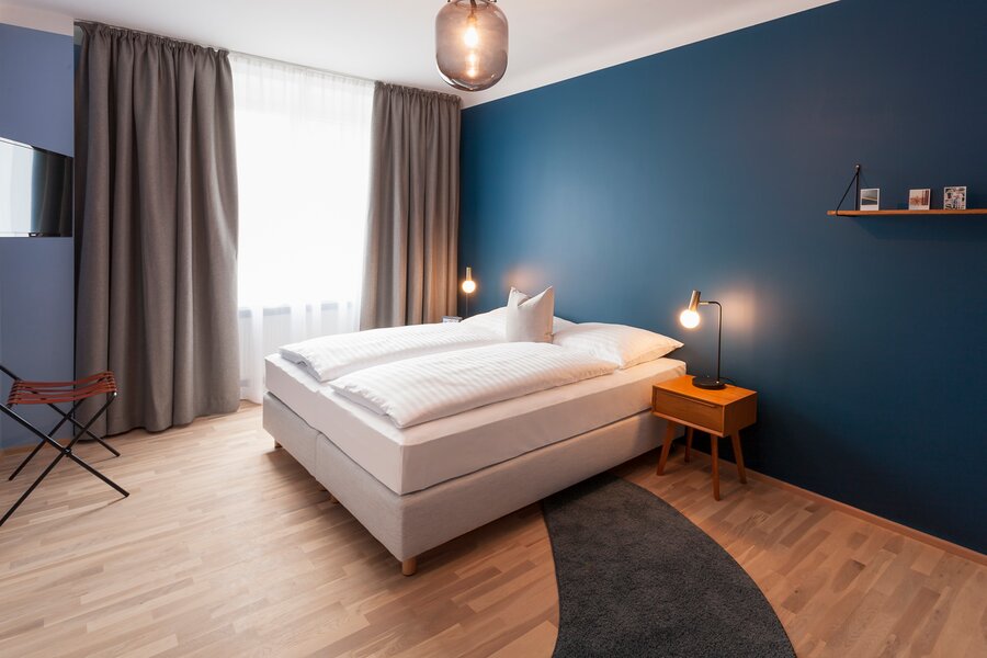 Bright bedroom with box spring bed & wood floor – 3-room apartment for short-term rental & temporary housing for 1 to 6 months in Linz