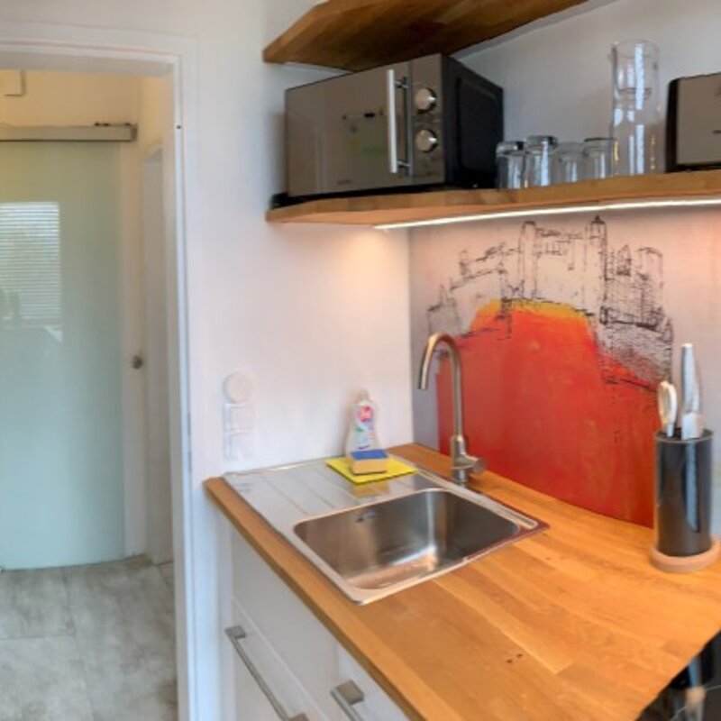 Bright kitchen with wooden countertop & cityscape mural – 1-room apartment, short-term rental, temporary housing for 1 to 6 months, Salzburg