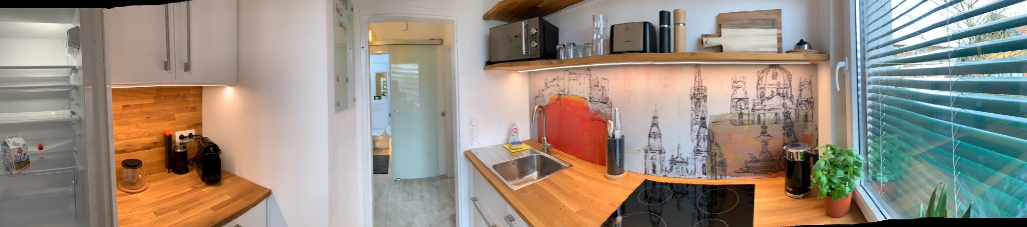 Bright kitchen with wooden countertop & cityscape mural – 1-room apartment, short-term rental, temporary housing for 1 to 6 months, Salzburg