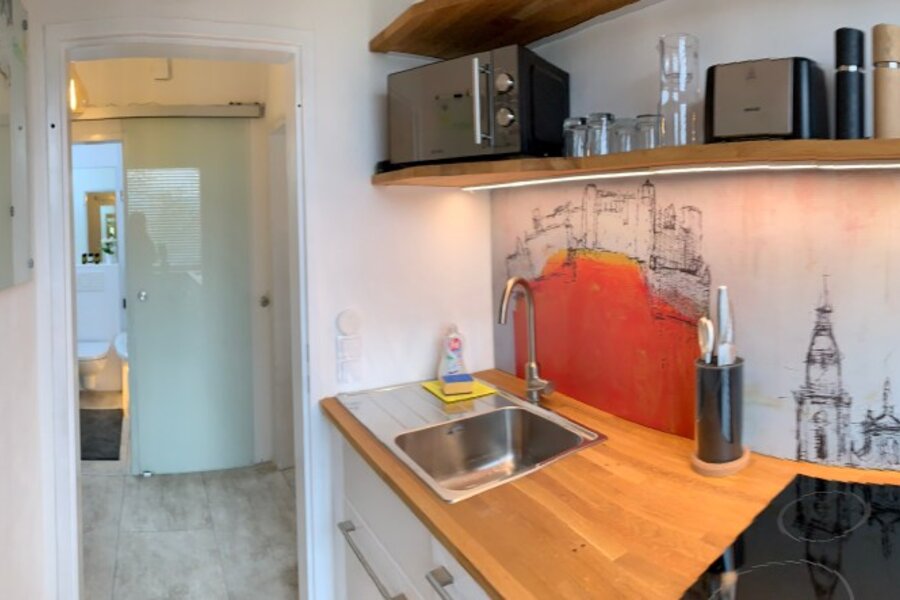 Bright kitchen with wooden countertop & cityscape mural – 1-room apartment, short-term rental, temporary housing for 1 to 6 months, Salzburg