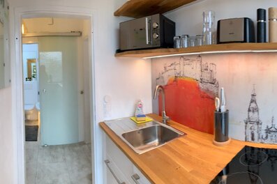 Bright kitchen with wooden countertop & cityscape mural – 1-room apartment, short-term rental, temporary housing for 1 to 6 months, Salzburg