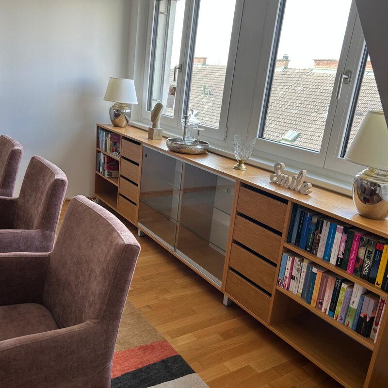 Bright living room with armchairs & bookshelf – 3-room apartment for short-term rental & temporary housing for 1 to 6 months in Schwechat