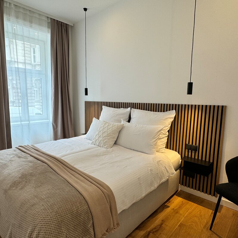 The bedroom features a large, comfortable box spring bed and modern lighting. The quiet and stylish decor ensures restful sleep and a relaxing atmosphere.