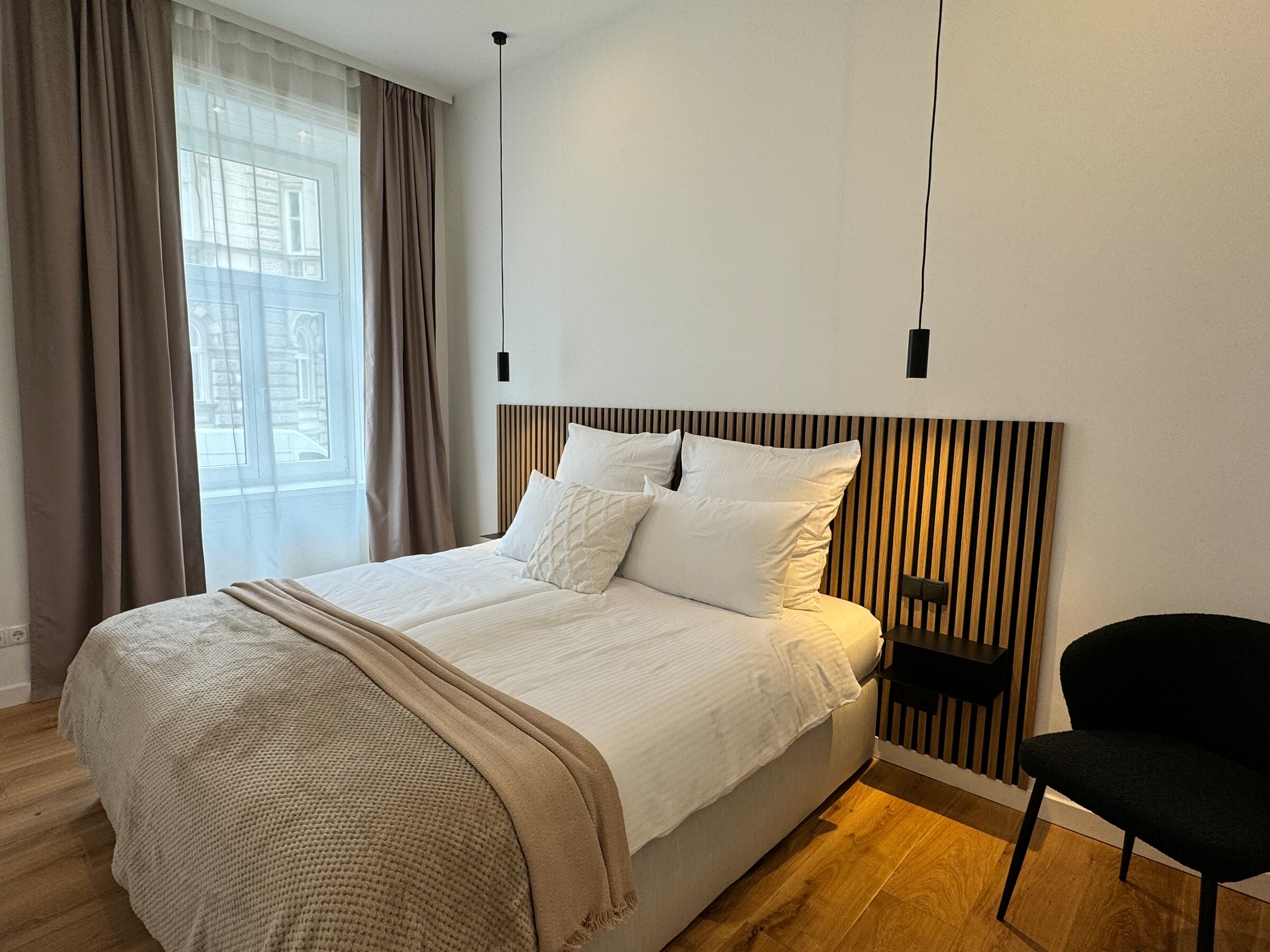 The bedroom features a large, comfortable box spring bed and modern lighting. The quiet and stylish decor ensures restful sleep and a relaxing atmosphere.