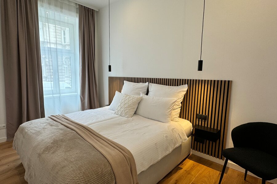 The bedroom features a large, comfortable box spring bed and modern lighting. The quiet and stylish decor ensures restful sleep and a relaxing atmosphere.
