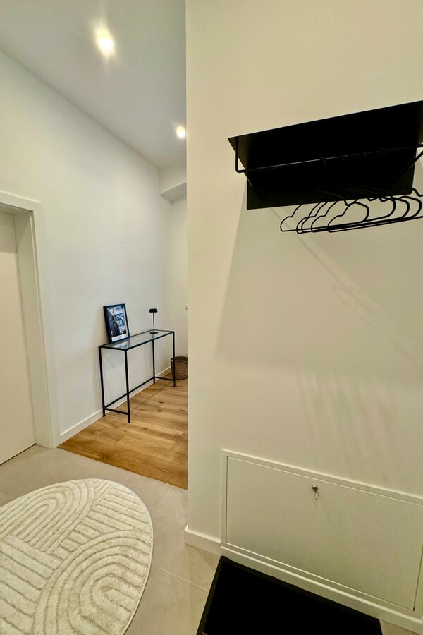 Der einladende Eingangsbereich und Flur bieten ausreichend Platz, um in Ruhe anzukommen und Ihre Kleidung sowie Gepäck bequem abzulegen. Die moderne Einrichtung und die stilvollen Details schaffen eine angenehme Atmosphäre.