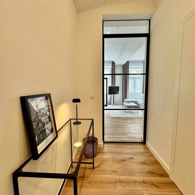 Der stilvolle Flur führt durch eine elegante Loft-Tür in den offenen Wohnbereich. Diese Kombination aus modernem Design und transparenten Elementen schafft ein helles und einladendes Ambiente.