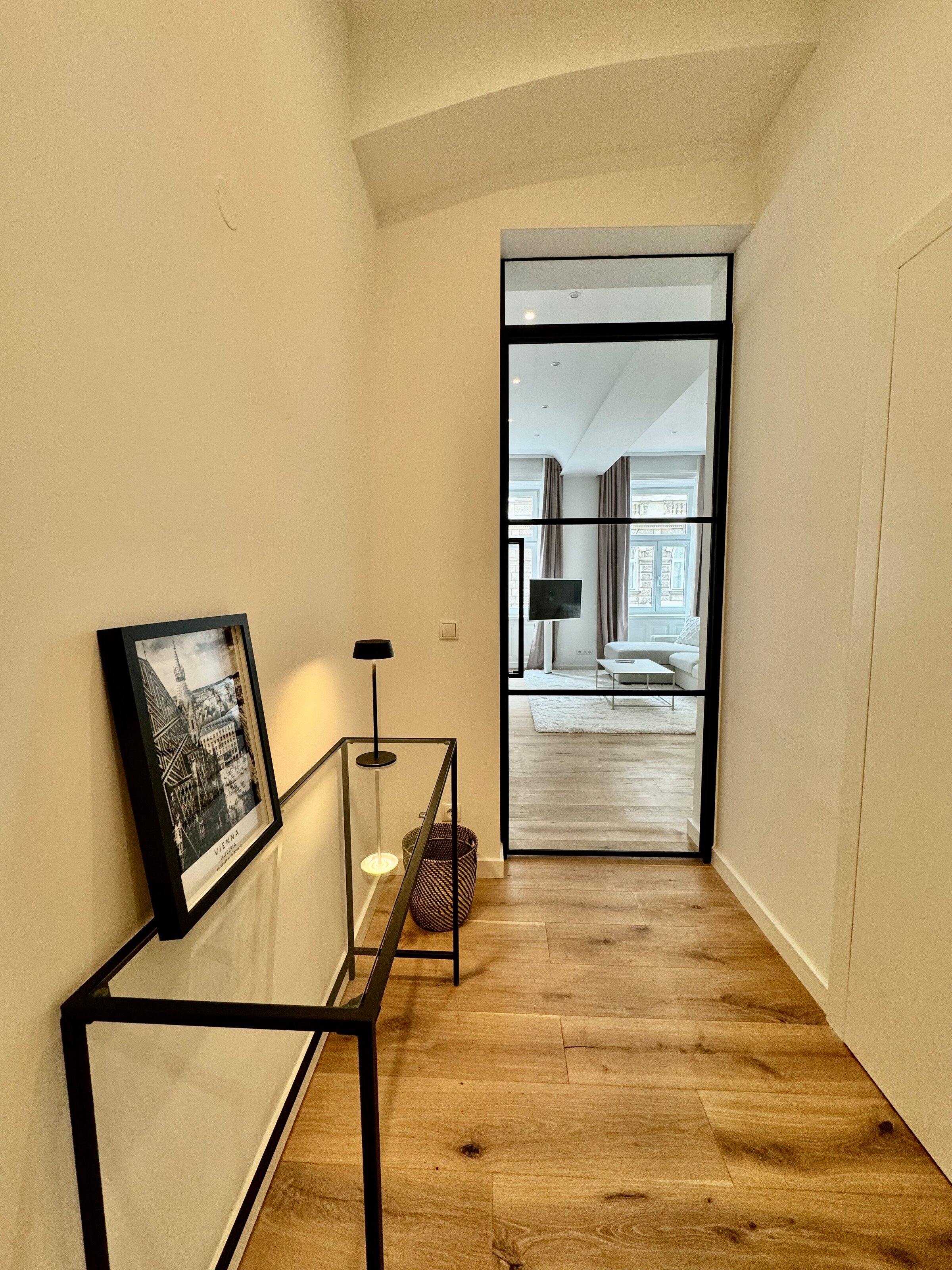 Der stilvolle Flur führt durch eine elegante Loft-Tür in den offenen Wohnbereich. Diese Kombination aus modernem Design und transparenten Elementen schafft ein helles und einladendes Ambiente.