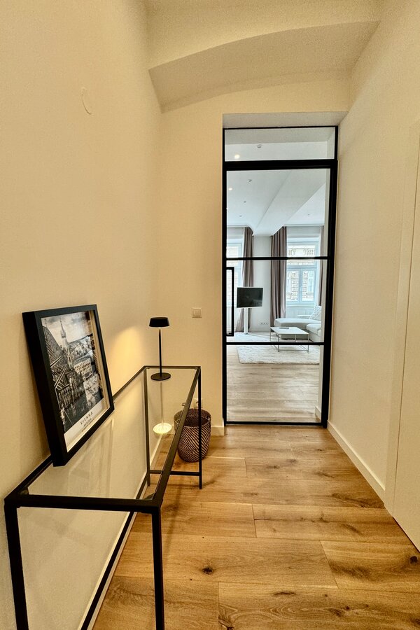 Der stilvolle Flur führt durch eine elegante Loft-Tür in den offenen Wohnbereich. Diese Kombination aus modernem Design und transparenten Elementen schafft ein helles und einladendes Ambiente.