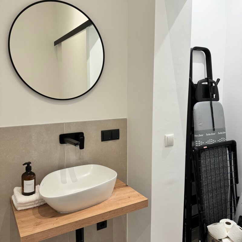 Die elegante Gästetoilette verfügt über ein modernes Waschbecken und eine geöffnete Schiebetür, die den zusätzlichen Stauraum zeigt.