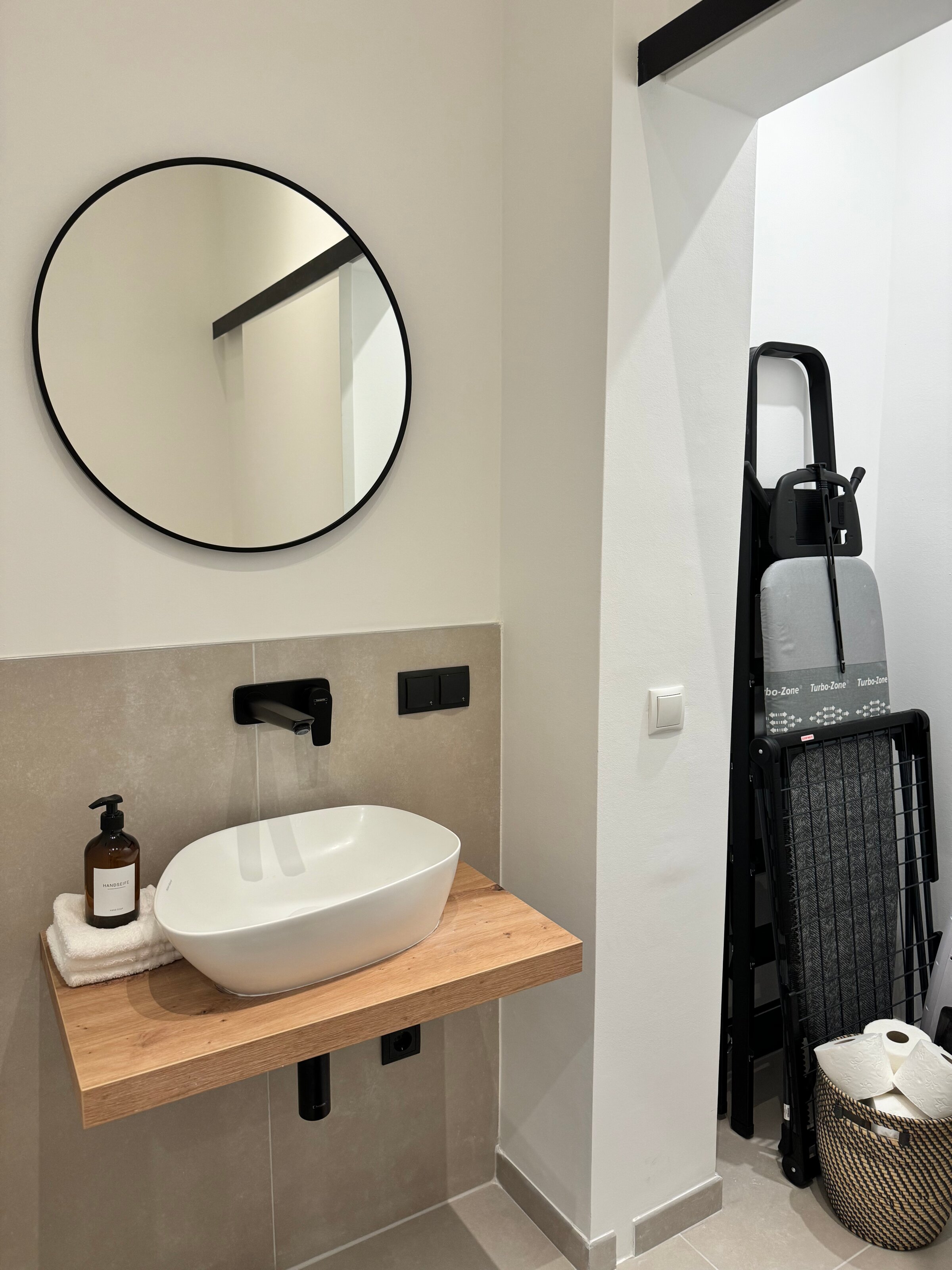 Die elegante Gästetoilette verfügt über ein modernes Waschbecken und eine geöffnete Schiebetür, die den zusätzlichen Stauraum zeigt.