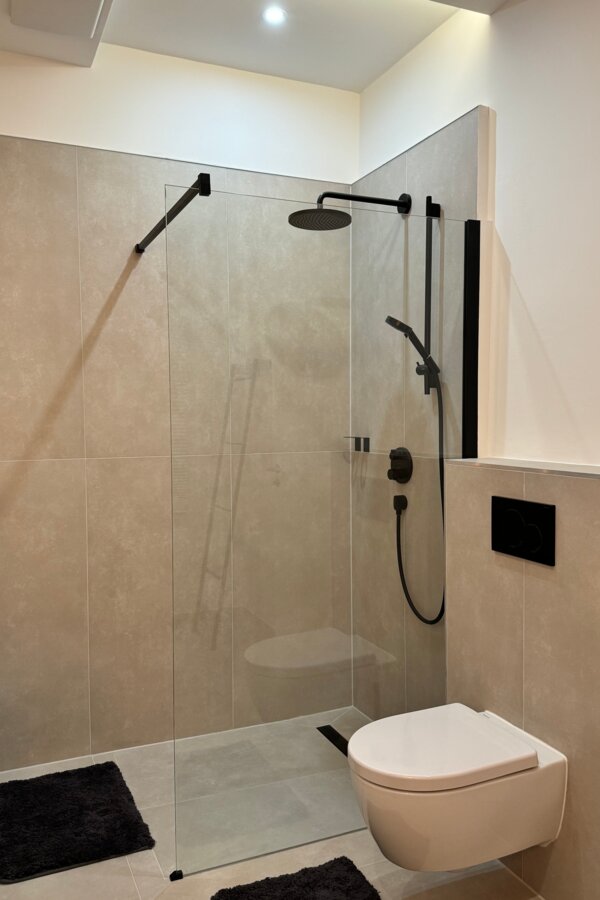 Die geräumige und stilvolle Dusche im Badezimmer bietet höchsten Komfort und moderne Armaturen. Die klaren Linien und das elegante Design sorgen für ein luxuriöses Duscherlebnis.