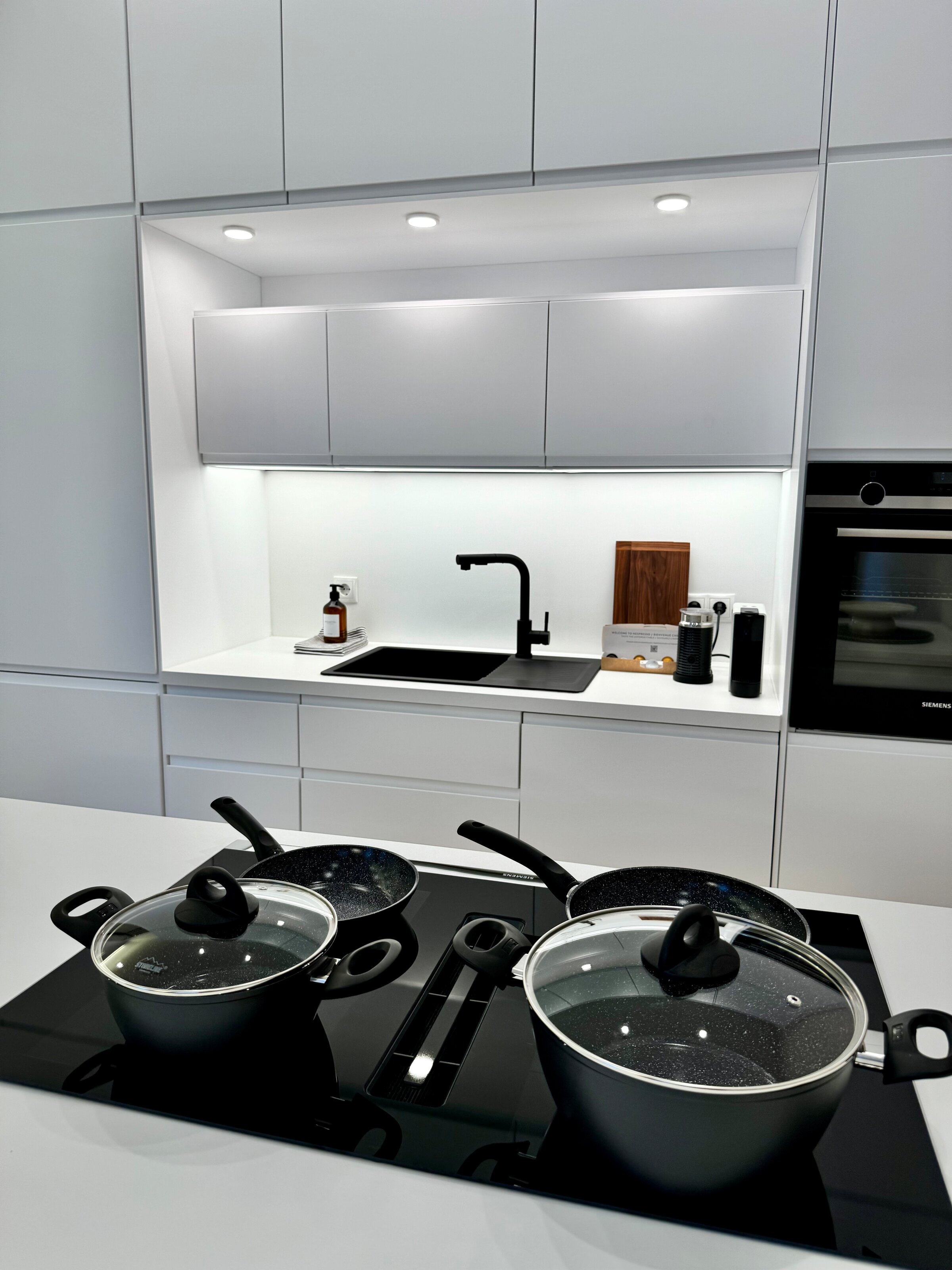 Die voll ausgestattete Küche ist mit hochwertigen Geräten und allen notwendigen Utensilien ausgestattet. Das minimalistische Design und die klaren Linien schaffen eine elegante und funktionale Arbeitsumgebung.