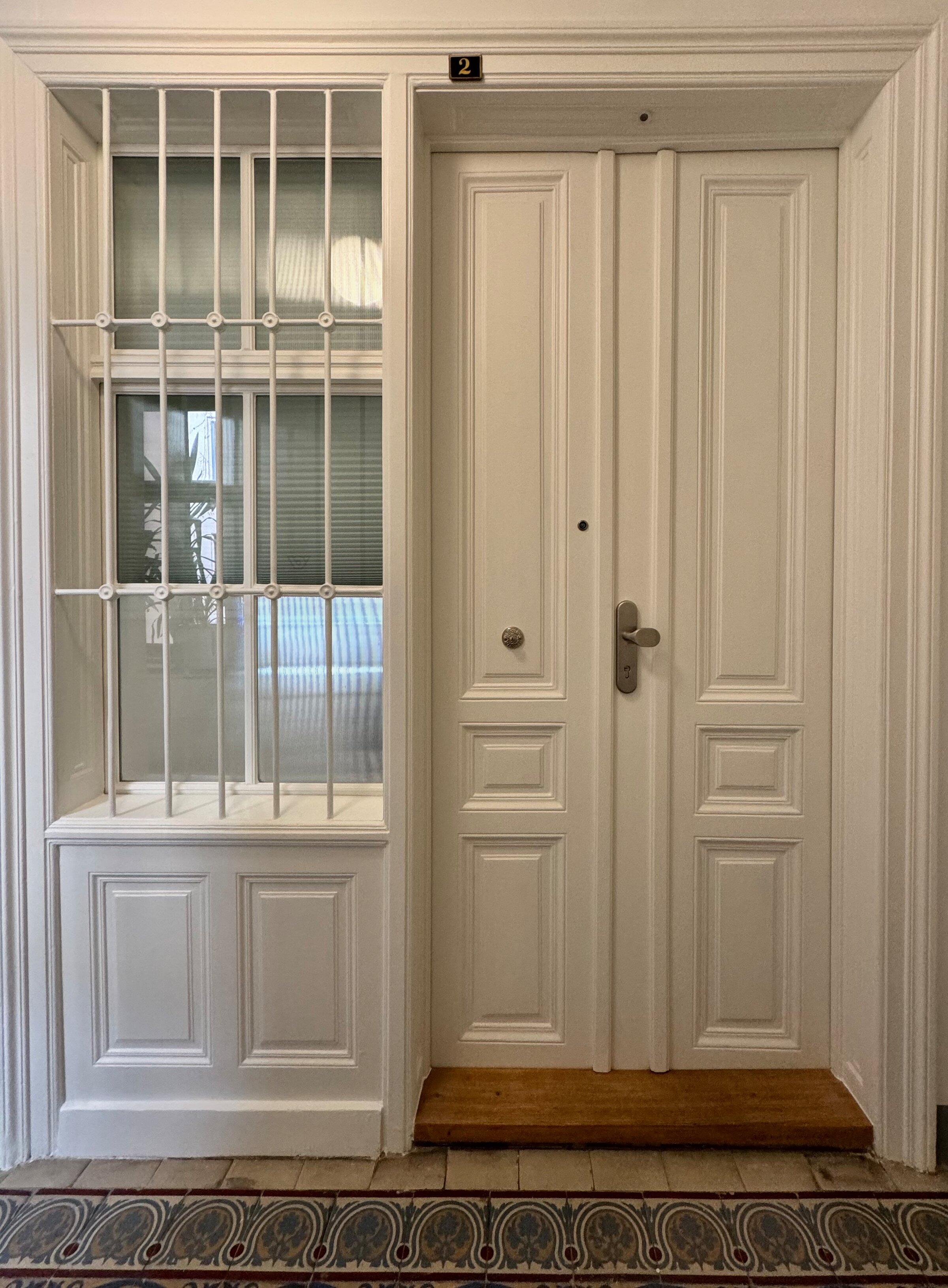 Die Eingangstür der Wohnung von außen. Das Fenster aus geriffeltem Glas zum Hausflur lässt Licht in die Wohnung und kann mit einem Rollo verdunkelt werden. Es sorgt zusätzlich für ausreichenden Sichtschutz und gewährleistet Privatsphäre.