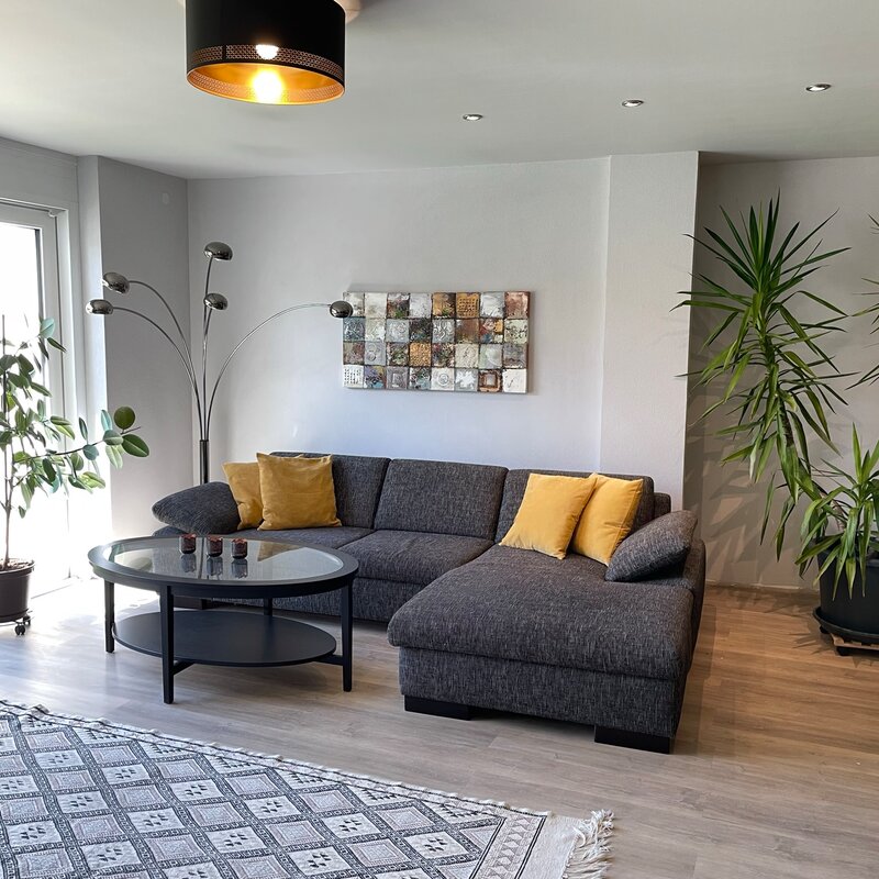 Bright living room with corner sofa and plants – 3-room apartment, short-term rental in Pfaffenweiler, temporary housing for 1 to 6 months