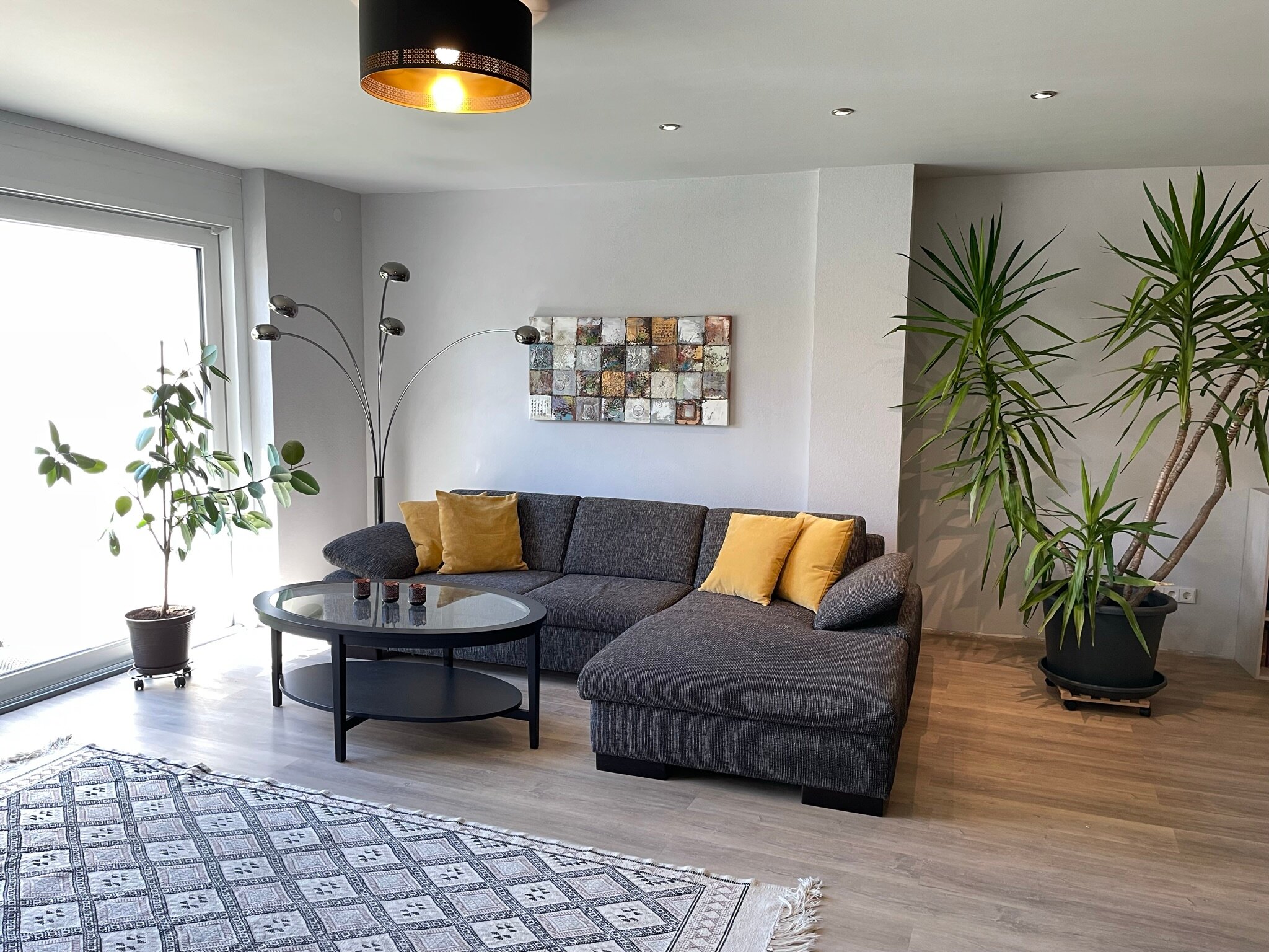 Bright living room with corner sofa and plants – 3-room apartment, short-term rental in Pfaffenweiler, temporary housing for 1 to 6 months