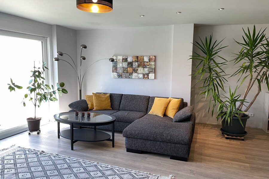 Bright living room with corner sofa and plants – 3-room apartment, short-term rental in Pfaffenweiler, temporary housing for 1 to 6 months