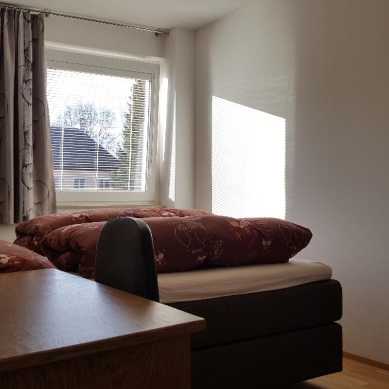 Das Schlafzimmer ist auf einen grünen Innenhof augerichtet und mit einen großen Boxspring Bett, einem großen Schrank und einem Schreibtisch ausgestattet.