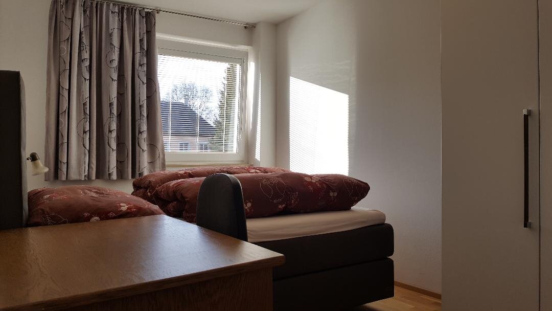 Das Schlafzimmer ist auf einen grünen Innenhof augerichtet und mit einen großen Boxspring Bett, einem großen Schrank und einem Schreibtisch ausgestattet.