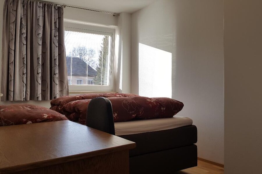 Das Schlafzimmer ist auf einen grünen Innenhof augerichtet und mit einen großen Boxspring Bett, einem großen Schrank und einem Schreibtisch ausgestattet.