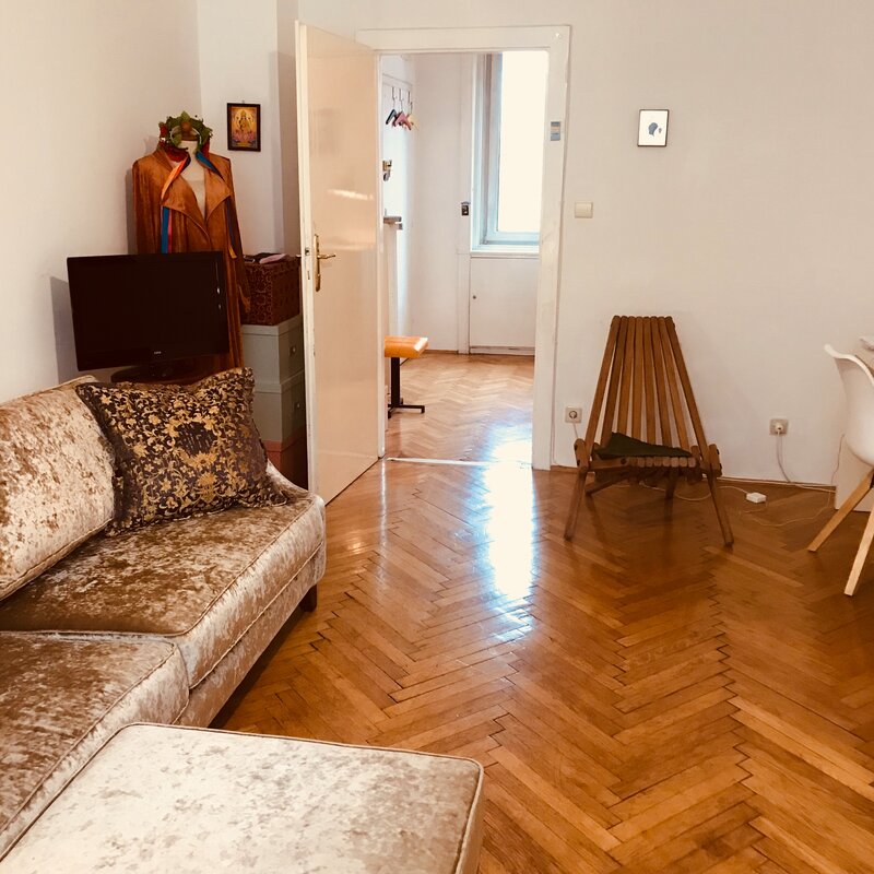 Helles Wohnzimmer mit Fischgrätparkett, Samtsofa & Arbeitsplatz – 2-Zimmer Wohnung zur Kurzzeitmiete Wien