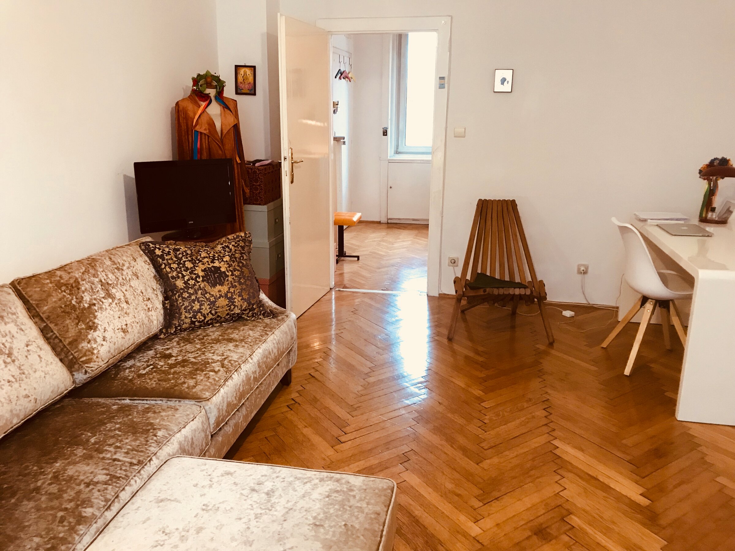 Helles Wohnzimmer mit Fischgrätparkett, Samtsofa & Arbeitsplatz – 2-Zimmer Wohnung zur Kurzzeitmiete Wien