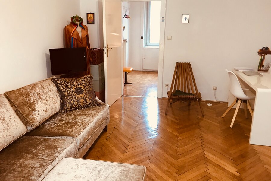 Helles Wohnzimmer mit Fischgrätparkett, Samtsofa & Arbeitsplatz – 2-Zimmer Wohnung zur Kurzzeitmiete Wien