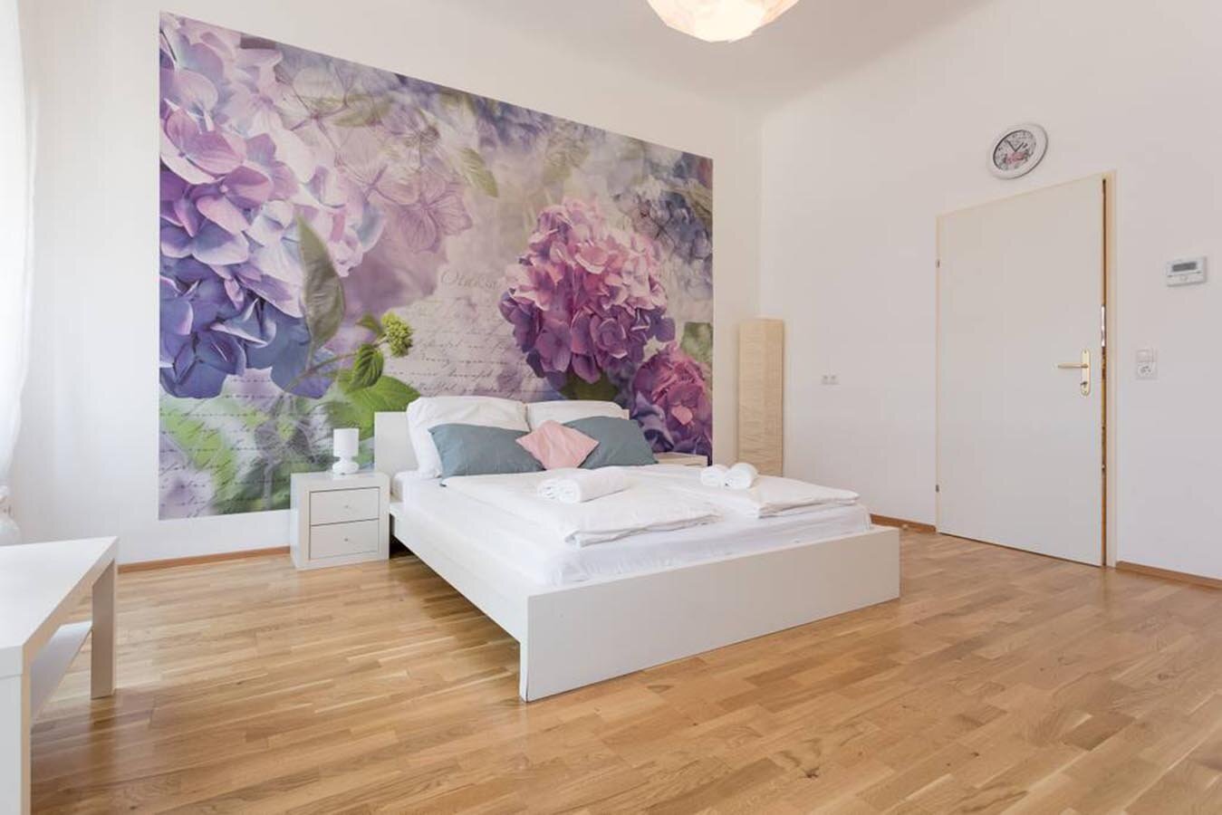 Helles Schlafzimmer mit floralem Wandbild – 3-Zimmer Wohnung zur Kurzzeitmiete & Wohnen auf Zeit für 1 bis 6 Monate in Wien