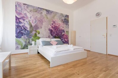 Helles Schlafzimmer mit floralem Wandbild – 3-Zimmer Wohnung zur Kurzzeitmiete & Wohnen auf Zeit für 1 bis 6 Monate in Wien