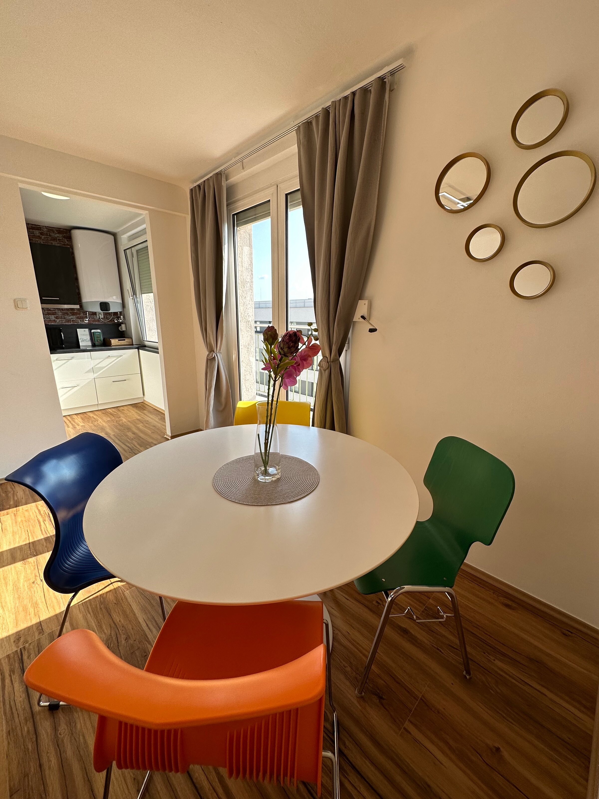 Dining area with colorful chairs & balcony – 3-room apartment, short-term rental & temporary housing for 1 to 6 months in Graz