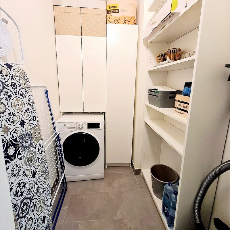 Abstellraum mit Waschmaschine, Dampfbügestation, Bügelbrett, Wäscheständer, Staubsauger und diversen Reinigungsutensilien