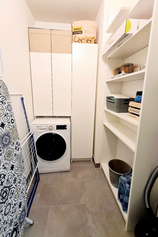 Abstellraum mit Waschmaschine, Dampfbügestation, Bügelbrett, Wäscheständer, Staubsauger und diversen Reinigungsutensilien