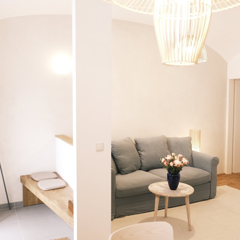 Helles Wohnzimmer mit Sofa & Rattanlampe – 2-Zimmer Wohnung zur Kurzzeitmiete, Wohnen auf Zeit für 1 bis 6 Monate in Wien