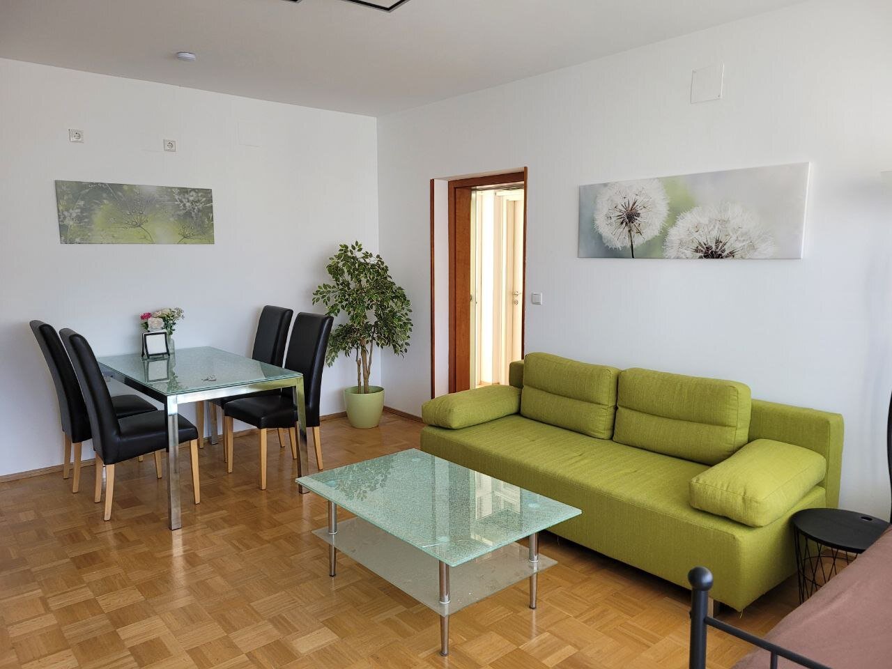 Bright living & dining area, glass table & green sofa – 3-room apartment, short-term rental Graz, temporary housing 1 to 6 months