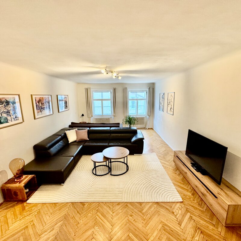 Bright living room with leather sofa & parquet – 2-room apartment, short-term rental, temporary housing for 1 to 6 months, Salzburg | © A.Kopp