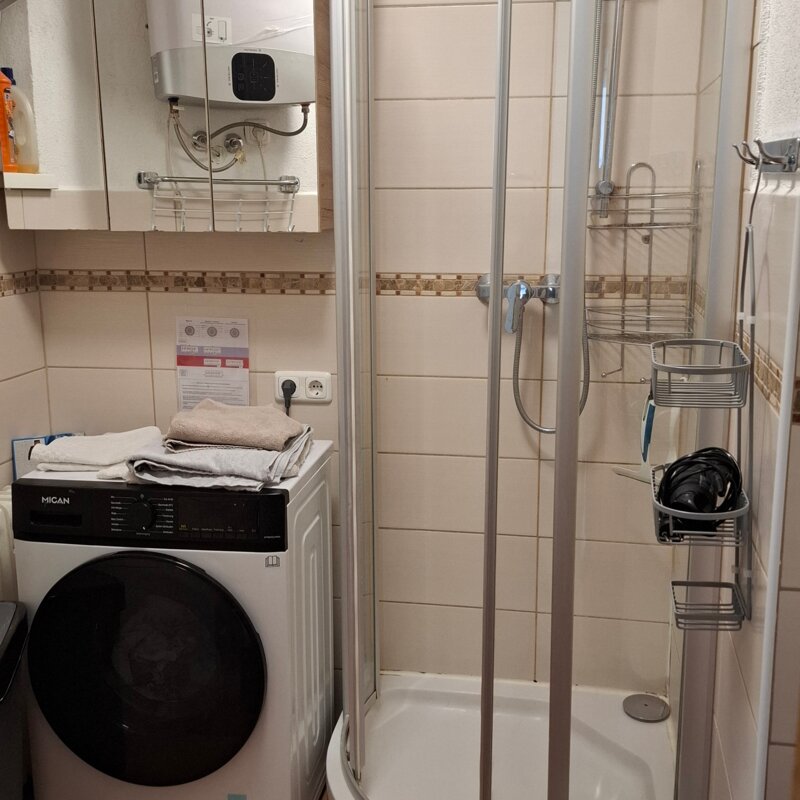 Bathroom with shower cubicle, washer-dryer machine and 150l hot water storage tank.