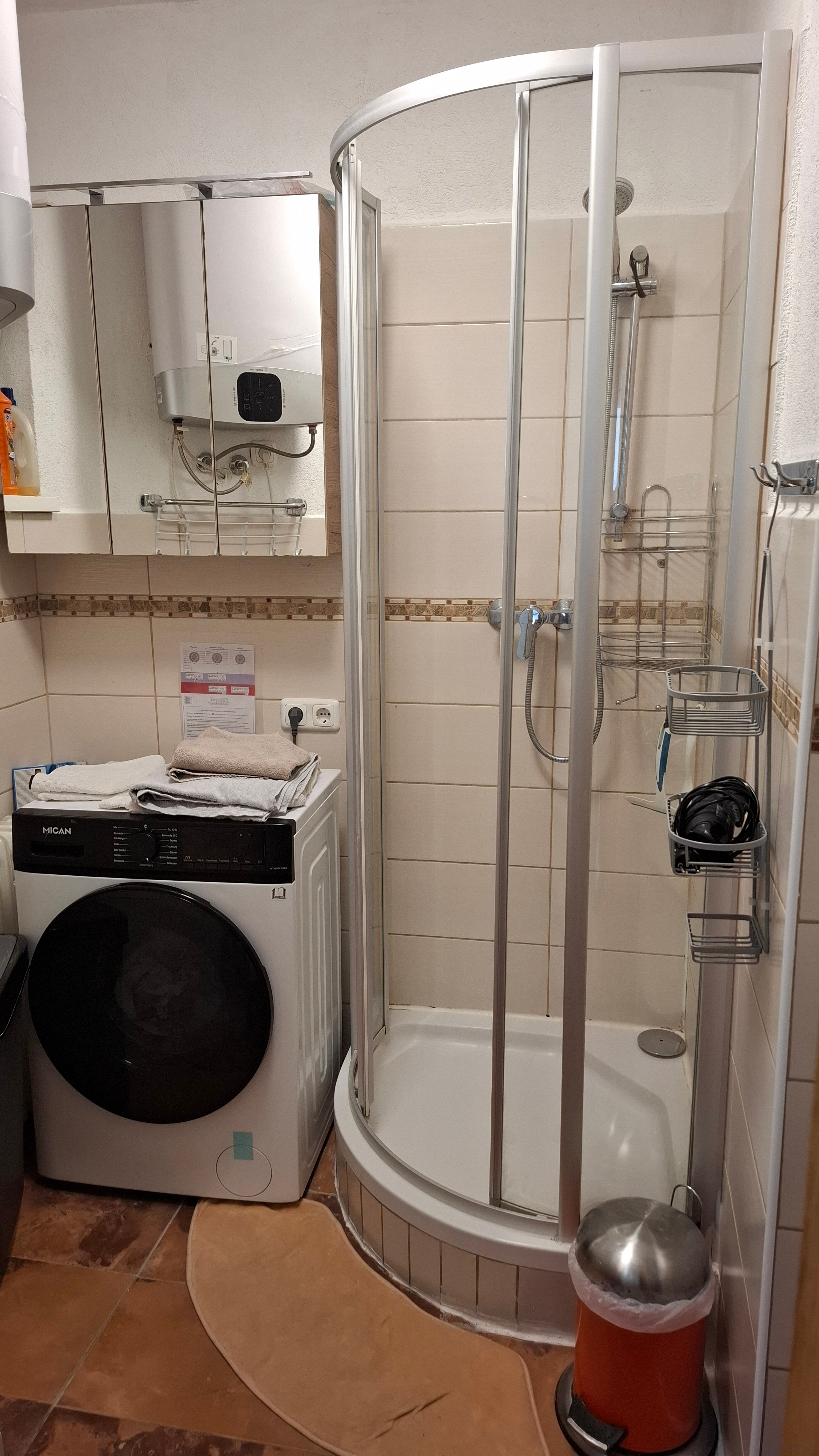 Bathroom with shower cubicle, washer-dryer machine and 150l hot water storage tank.