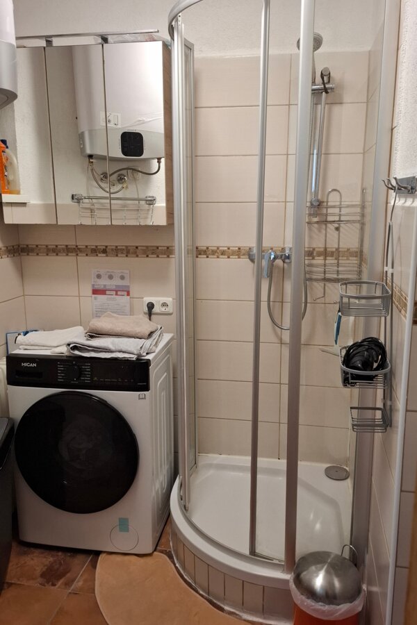 Bathroom with shower cubicle, washer-dryer machine and 150l hot water storage tank.