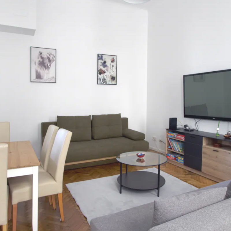 Wohnzimmer mit Esstisch, TV und Schlafcouch 