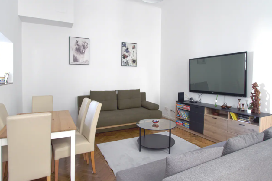 Wohnzimmer mit Esstisch, TV und Schlafcouch 