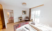 Schlafzimmer mit Schminktisch und Leseecke und Zugang zu Balkon mit Bergblick