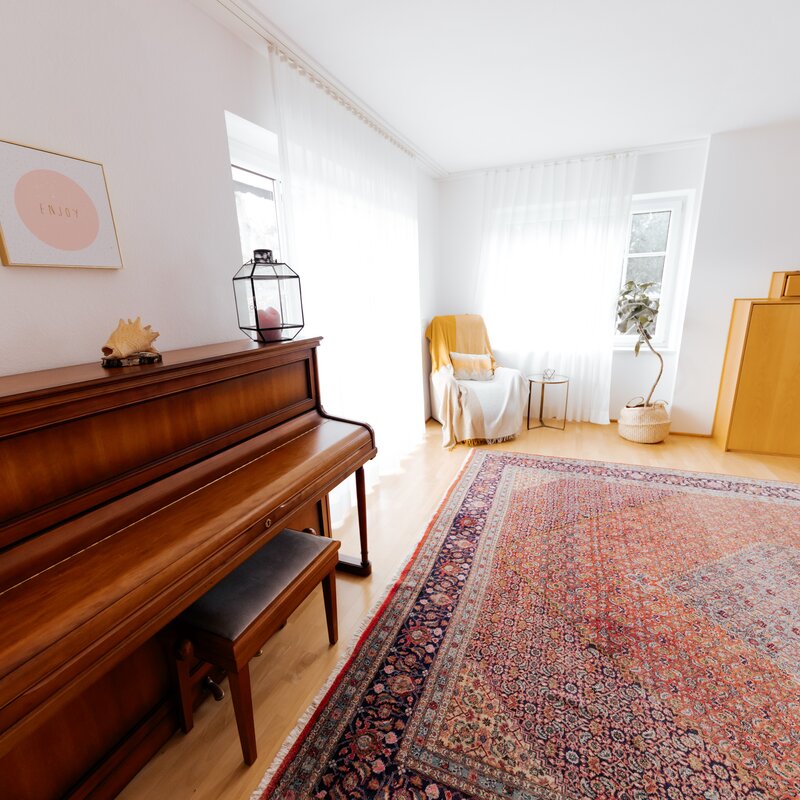 big, bright living room with piano, reading chair, TV and access to big terrace and garden