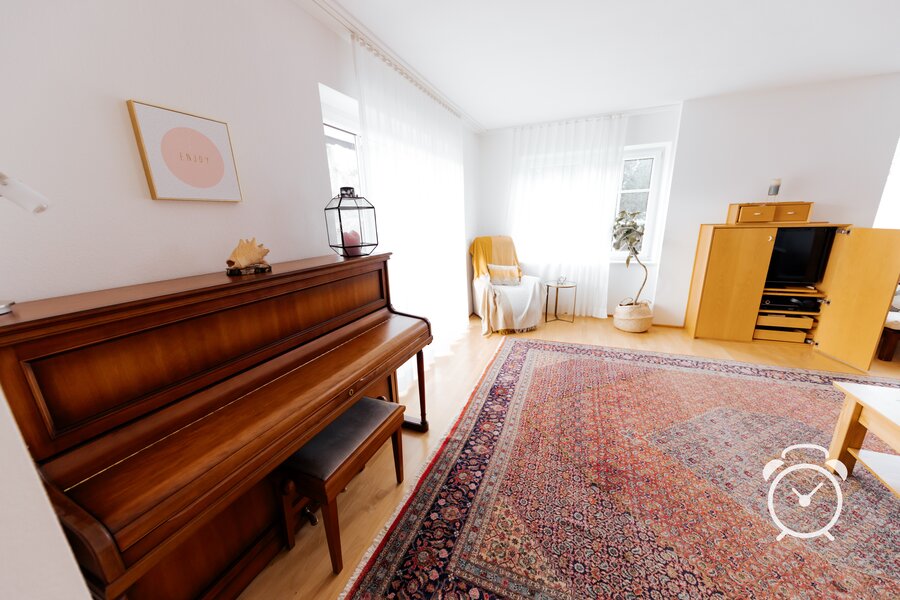 big, bright living room with piano, reading chair, TV and access to big terrace and garden