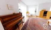 großes, helles Wohnzimmer mit Klavier, Leseecke, Fernseher und Zugang Terrasse