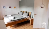helles, großes Schlafzimmer mit Doppelbett aus Zirbenholz und Panoramablick auf Untersberg und Zugang zu Balkon
